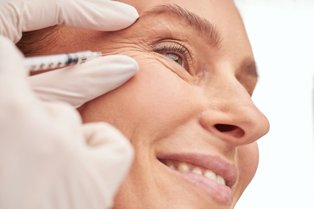 Beauty procedure. Close up of a beautiful mature woman receiving hyaluronic acid injection by