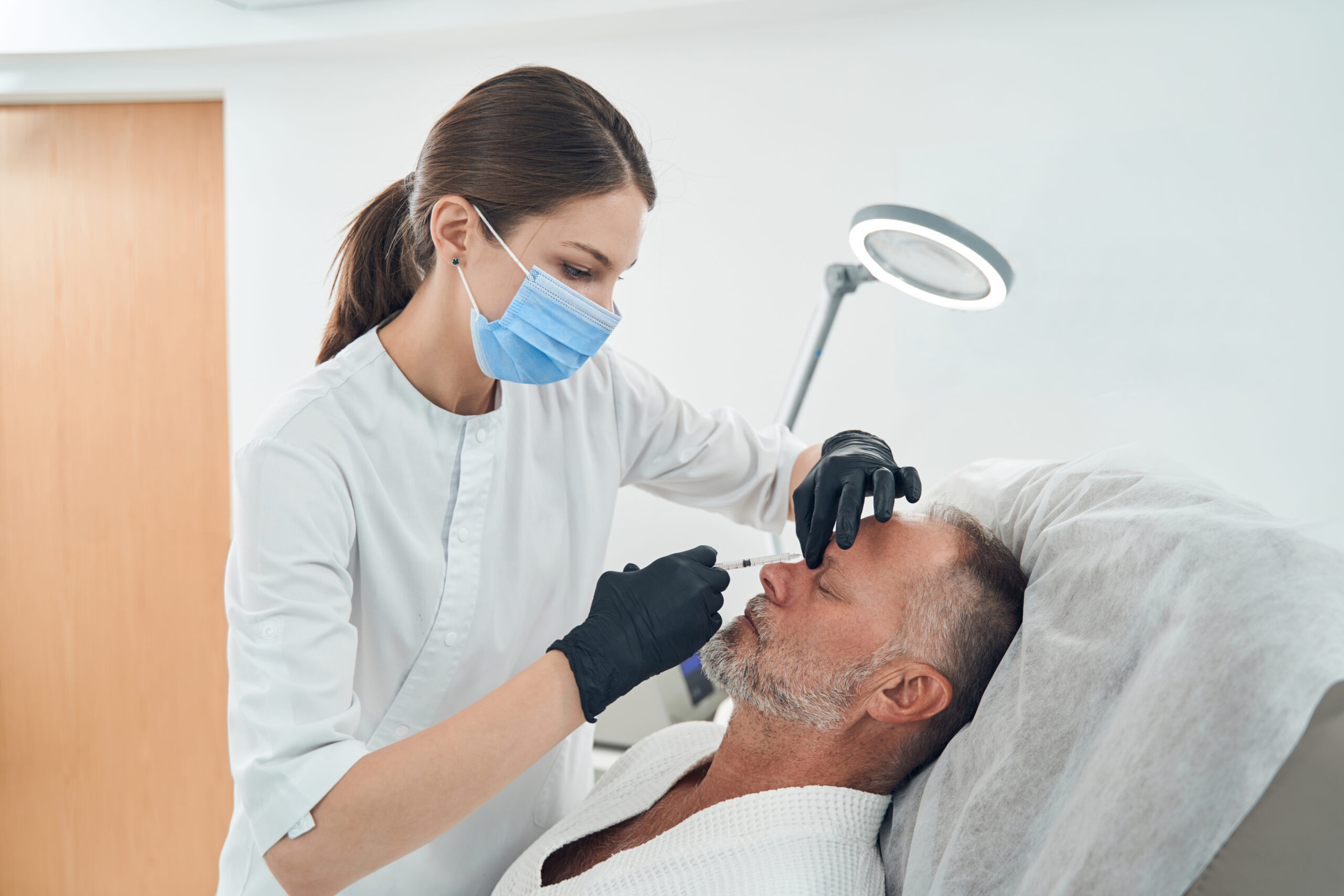 Man receiving cosmetic injection in cosmetology clinic