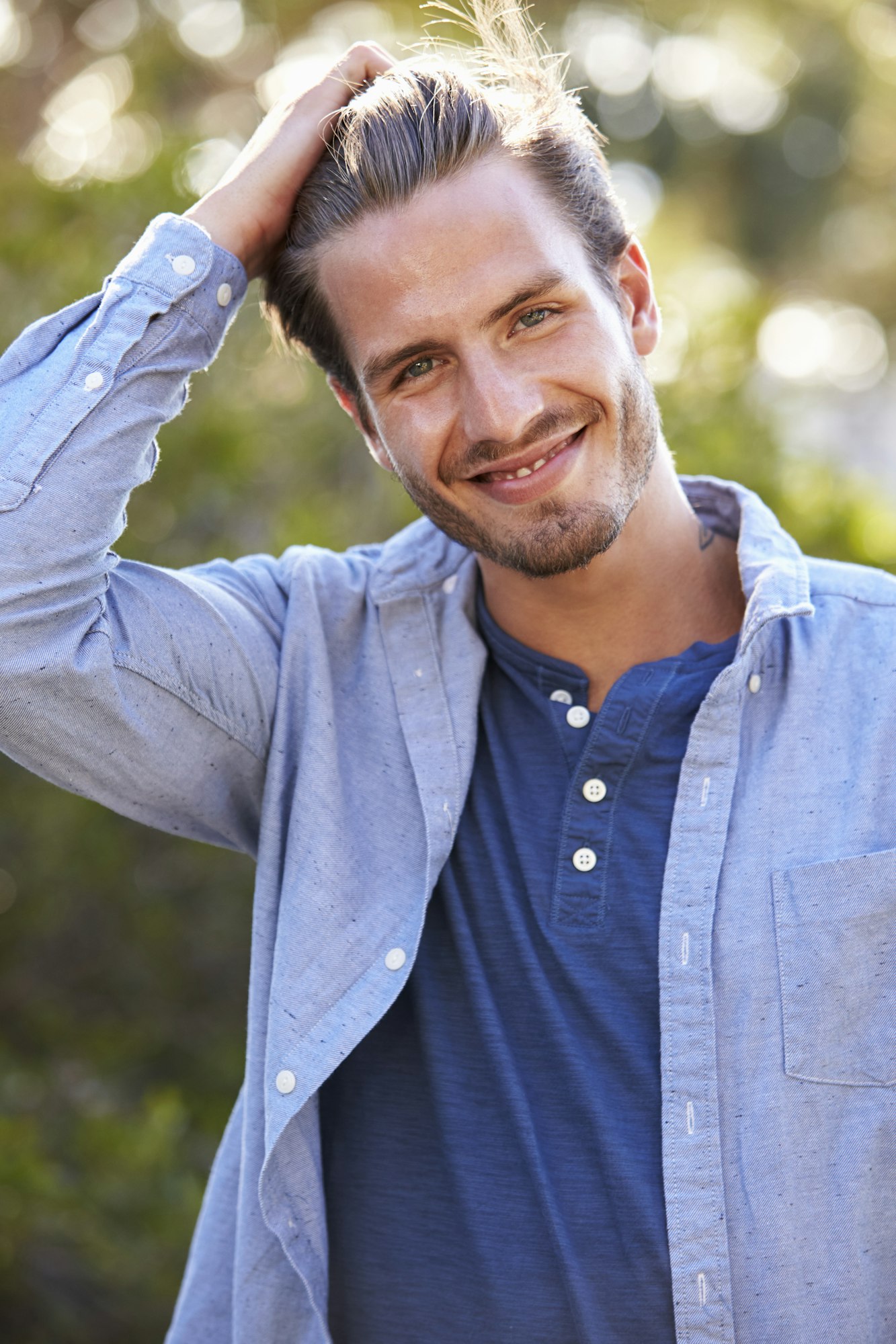 Portrait of young white man with hand in hair outdoors