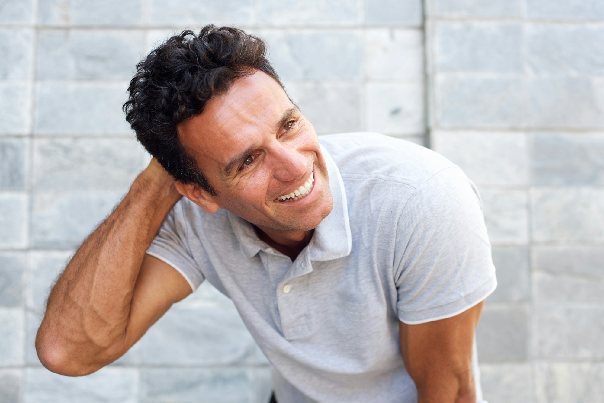 Handsome older man laughing with hand in hair 15 days after hair transplantation