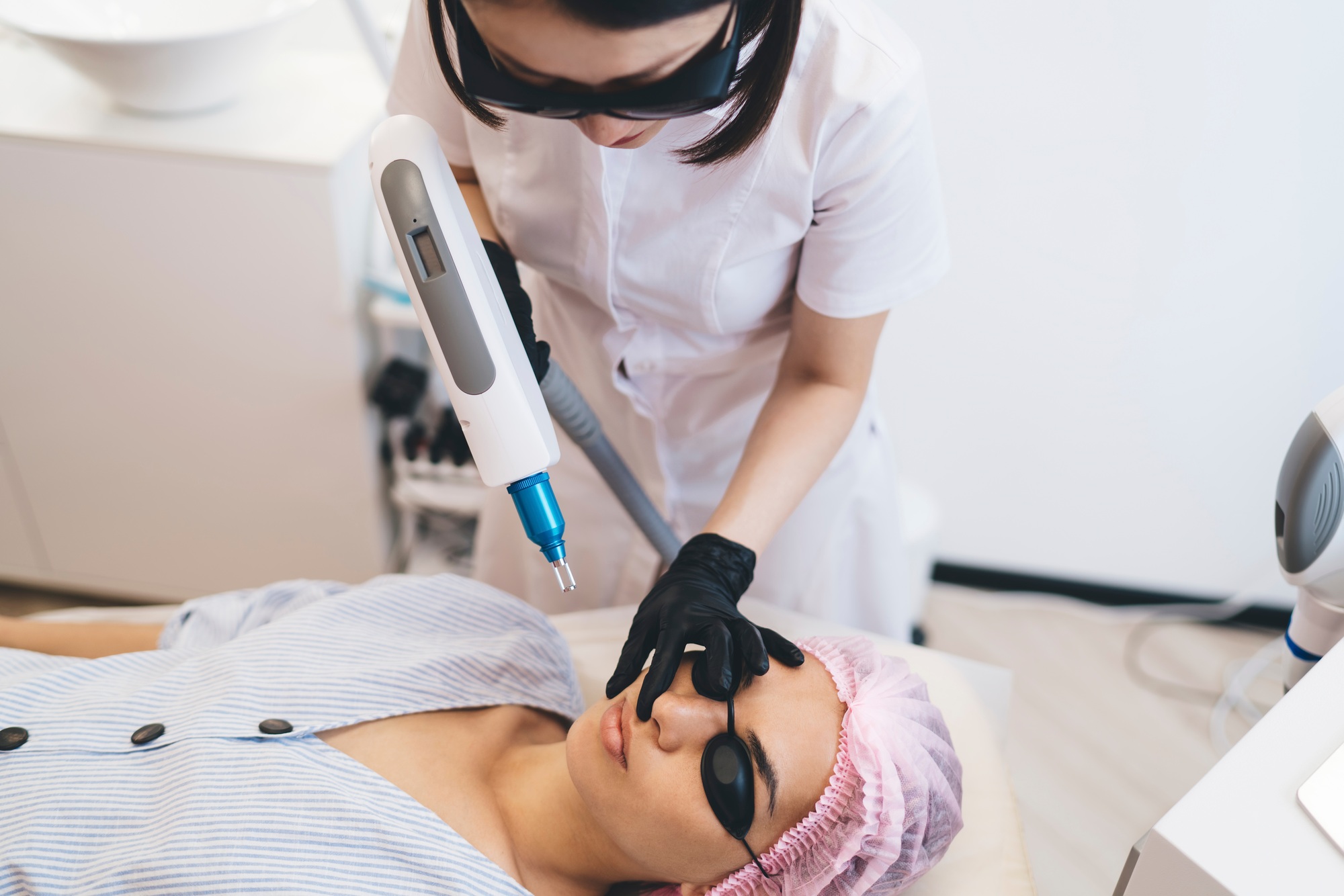 Woman lying while cosmetician doing photo epilation procedure