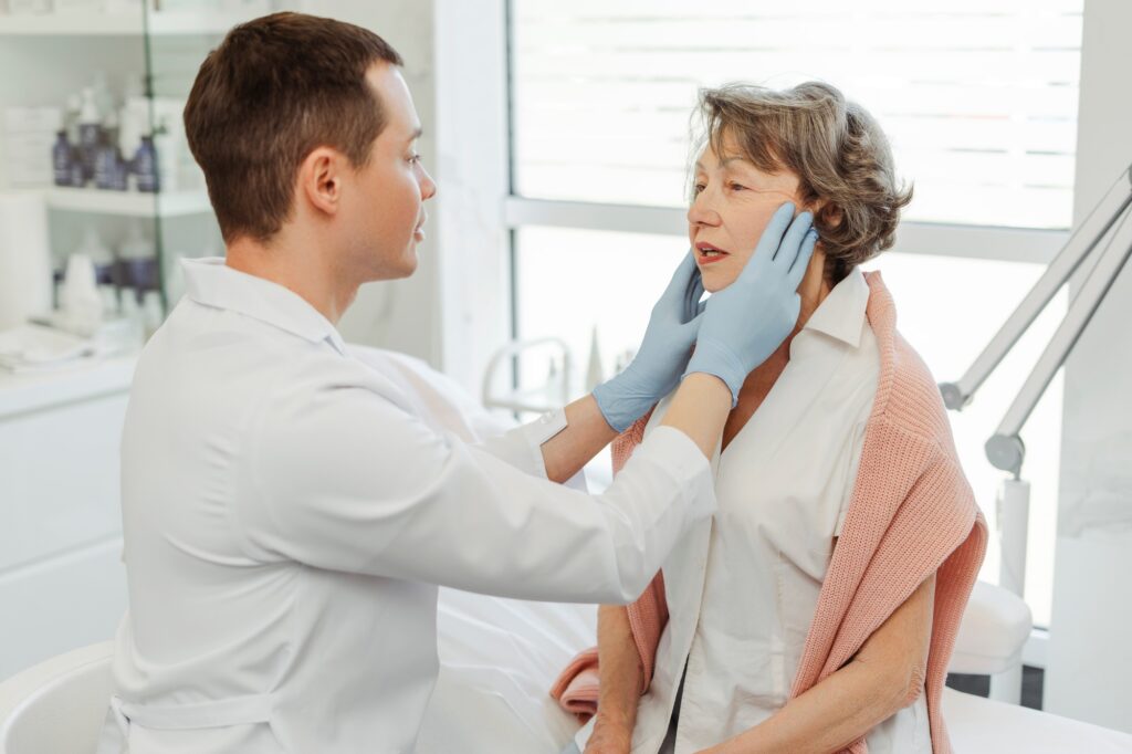 Attractive cosmetologist, man touching face of senior patient, lifting, tightening, rejuvenation