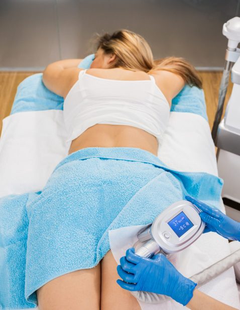 Beautician therapist applying cryolipolysis treatment in beauty salon.