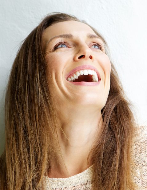 Beautiful middle aged woman laughing against white background