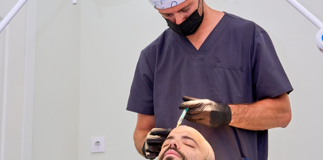 Doctor administering scalp injection during a hair transplant procedure on a patient