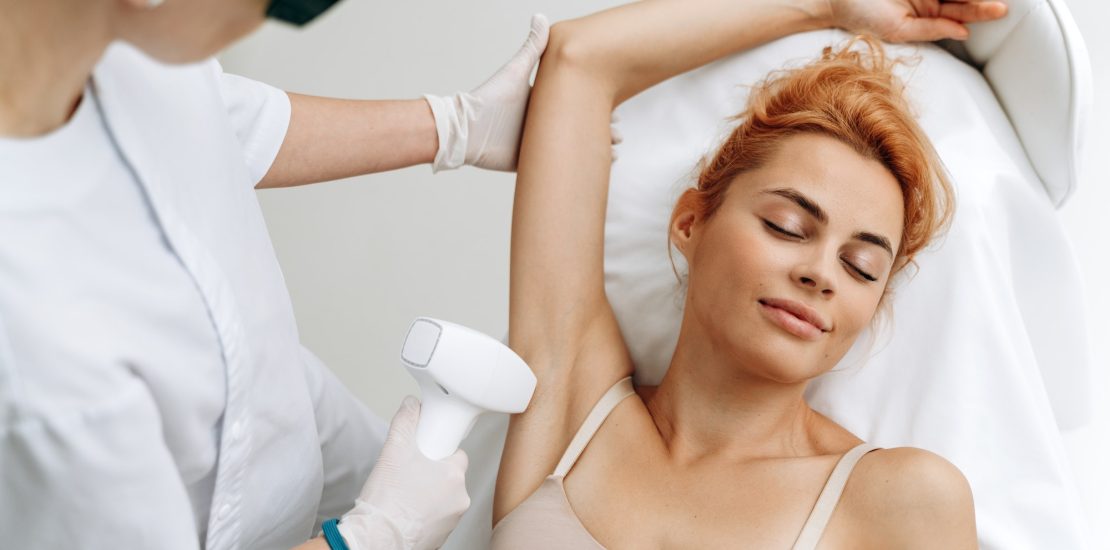 Portrait of young relaxed woman in underwear having professional laser epilation procedure of armpit