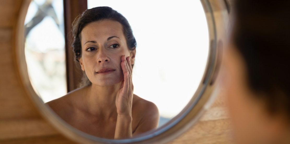 Woman looking at mirror worrying after oedema after hyaluronic acid injection