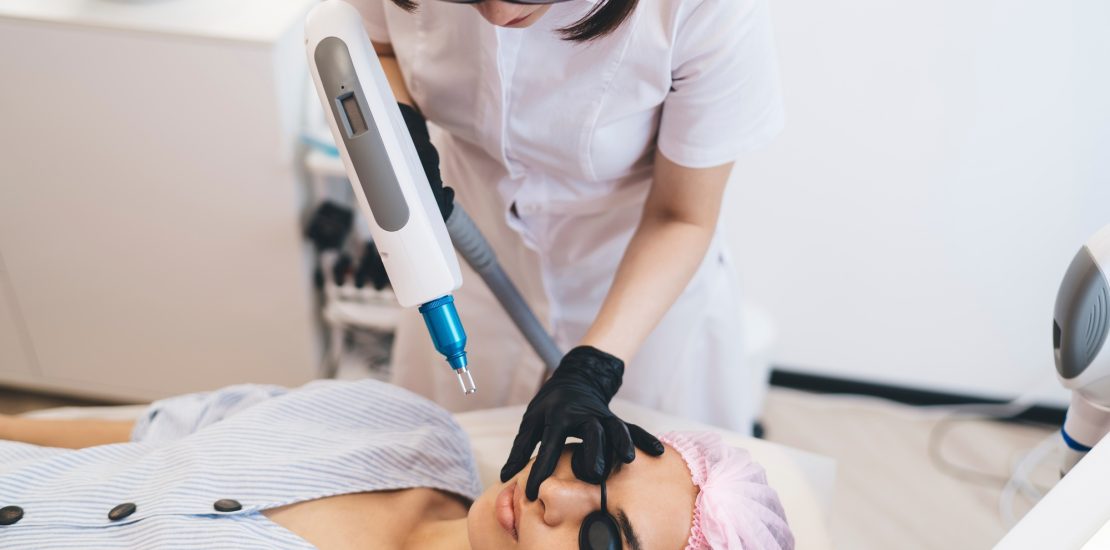 Woman lying while cosmetician doing photo epilation procedure