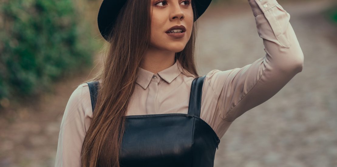 Woman wearing dress and a hat walking outside