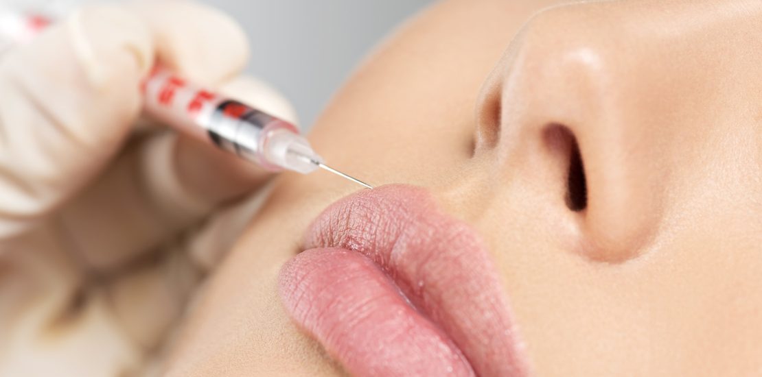 young woman gets botox injection in her lips