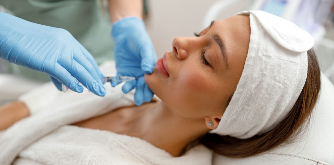 Young woman receiving hyaluronic acid injection in beauty salon